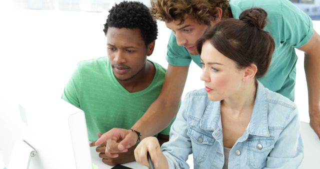 Young professionals collaborating on computer project. Diverse group intensely concentrating, discussing ideas, sharing opinions. Useful for corporate teamwork, tech innovation, office collaboration themed publications and websites.