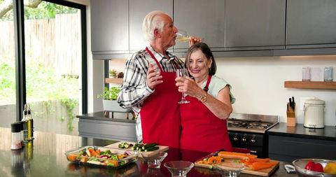 Senior Couple Cooking and Toasting in Modern Kitchen