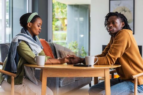 African american couple holding hands across table during emotional conversation at home