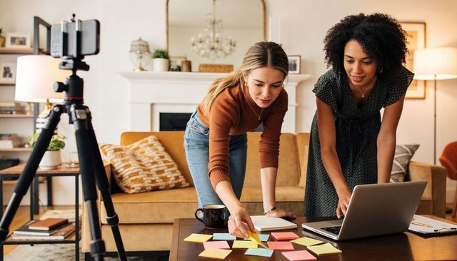 Two women collaborating and planning with sticky notes and laptop in cozy living room