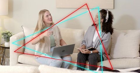 Two Women Collaborating on Couch Using Laptop and Notebook Casual Remote Work Conversation