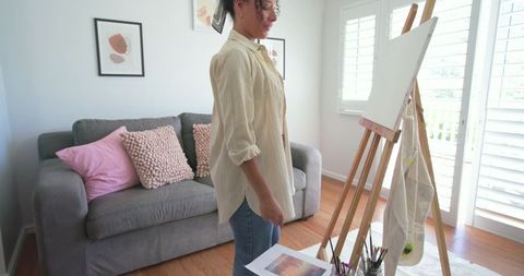 African american woman preparing canvas in bright living room art studio in soft light