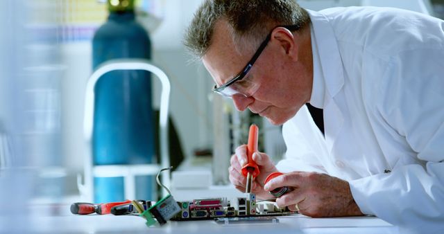 Technician wearing protective glasses repairs circuit board in laboratory, concentrating on precise soldering tasks. Suitable for use in articles on electronics, technical engineering, technical education, laboratory work, and high-tech vocational skills. Great for illustrating repair work, technical professions, and courses on electrical engineering.