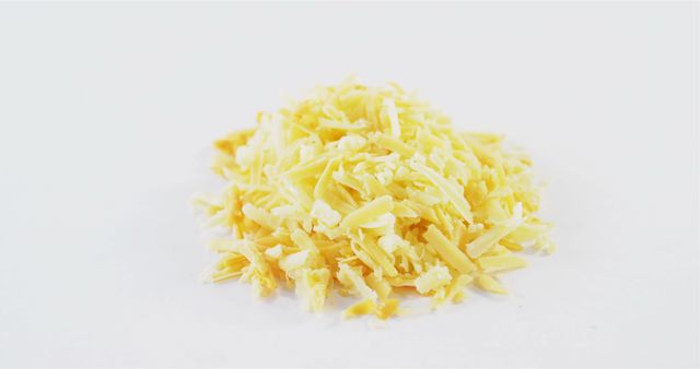 A pile of shredded yellow cheese is presented against a white background, with copy space. Shredded cheese is commonly used in cooking for its easy melting properties and ability to add flavor to dishes.