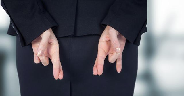 Businesswoman in a suit crossing fingers behind her back, symbolizing deception or dishonesty. Useful for illustrating concepts of trust, integrity, and hidden intentions in corporate environments. Ideal for articles, presentations, and marketing materials related to business ethics, trust issues, and professional behavior.