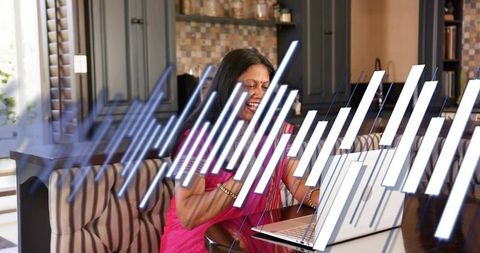 Indian woman in pink sari smiling while working on laptop with data visualization overlay
