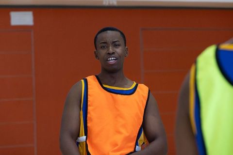 Athlete strategizing in gym wearing orange jersey