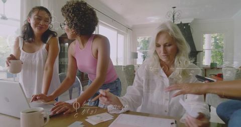 Multigenerational women collaborating and planning at cozy dining table with laptop