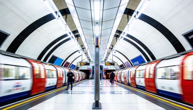 Symmetrical london underground platform with blurred trains and commuters walking