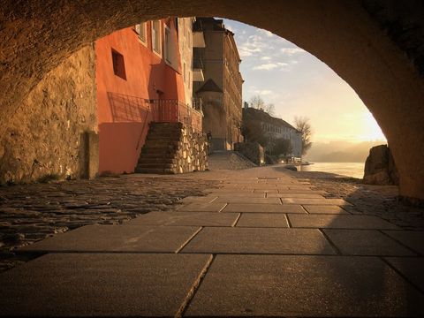 Scenic waterfront street under archway at sunrise