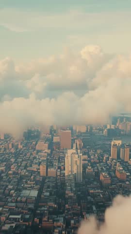 Gliding drone descending through low clouds revealing downtown skyline at golden hour