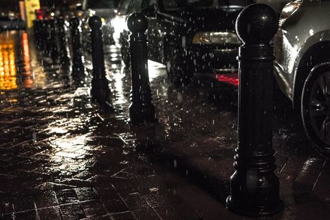 Rainy night street with silhouetted bollards and wet reflections