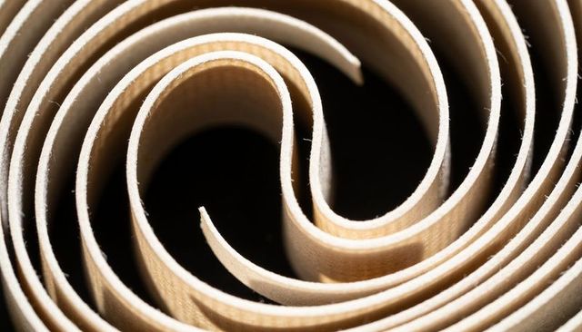 Spiraling wood veneer macro texture showing concentric grain and dark void