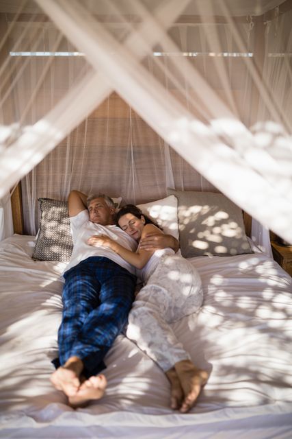 Couple relaxing in canopy bed during morning