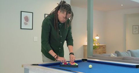 Mid-adult man arranging billiard balls on blue pool table in contemporary living room