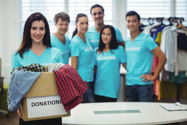 Portrait of female volunteer holding clothes in donation box at workshop