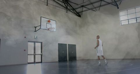 Basketball player shooting in indoor gym with intense focus