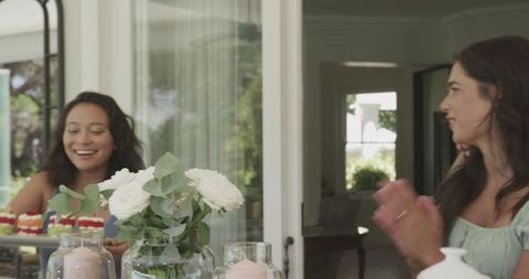 Friends Joyfully Celebrating at Home with Flowers and Drinks