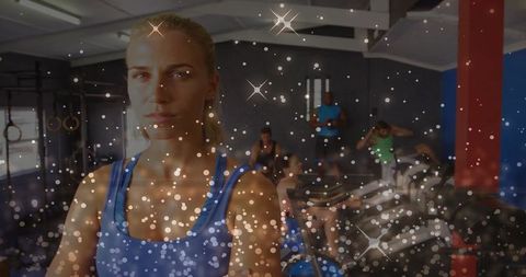 Focused blonde woman standing crossing arms in busy gym for strength and cardio training