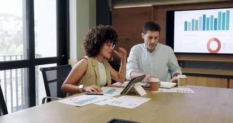 Coworkers Collaborating with Charts and Tablet at Modern Office