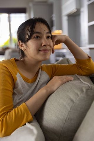 Young asian woman relaxing on sofa in cozy modern living room, minimalist lifestyle