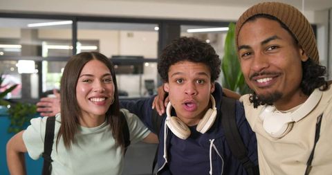 African american students smiling hanging out in campus hub with backpacks and headphones