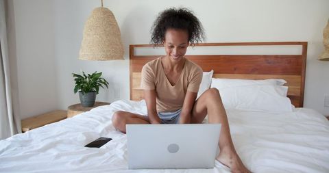 African American Woman Working on Laptop in Modern Minimalist Bedroom