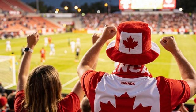 Passionate canadian soccer fans cheering in night stadium wearing maple leaf jersey