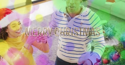 Couple decorating christmas tree together with baubles and festive bokeh merry christmas