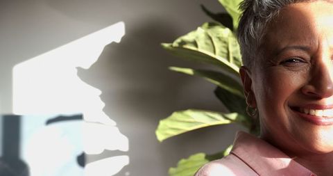 Senior Woman Smiling Near Potted Plant in Cozy Living Room