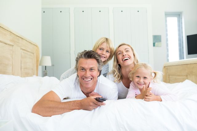 Happy family watching television in the bed room at home
