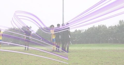 Soccer players forming defensive wall on grassy field with abstract purple motion overlay