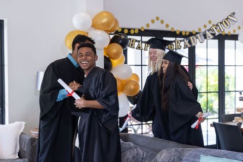Diverse Graduates Celebrating at Home Party with Balloons and Banners