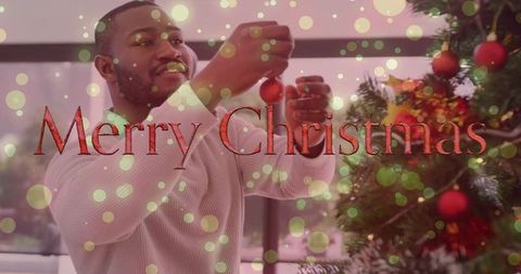 Merry christmas overlay on man decorating christmas tree with red baubles and bokeh lights