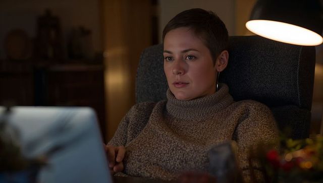 Working late in cozy knit turtleneck under warm lamp glow, remote work and evening focus
