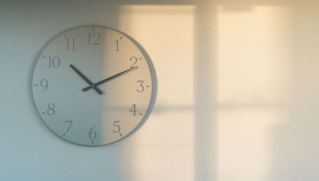 Sunlit minimalist wall clock casting window shadow with soft morning light