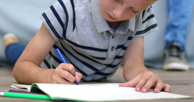 Young Boy Drawing With Blue Pen While Lying on Floor - Download Free Stock Images Pikwizard.com