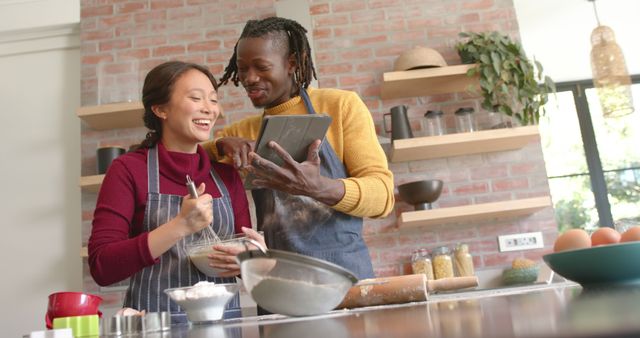 Happy couple engaged in baking together in a stylish, modern kitchen. The woman is mixing ingredients in a bowl while the man is holding a tablet, helping with the recipe. Ideal for concepts involving teamwork, family bonding, cooking, and modern lifestyle. Perfect for advertising cooking classes, kitchen appliances, or healthy living.