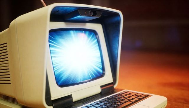 Retro cream crt terminal emitting blue light burst with vintage keyboard and glowing keys