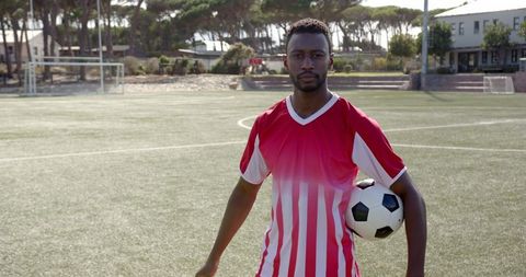 Focused Soccer Player Holding Ball on Field
