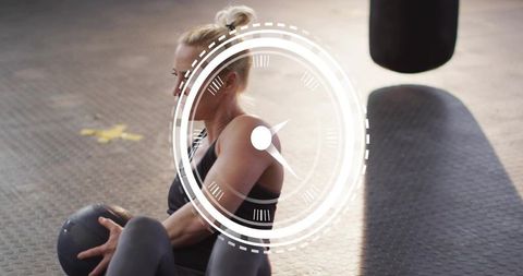 Female athlete performing russian twist with medicine ball and digital hud timer