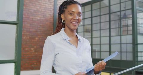 Confident professional woman holding folder in modern office environment