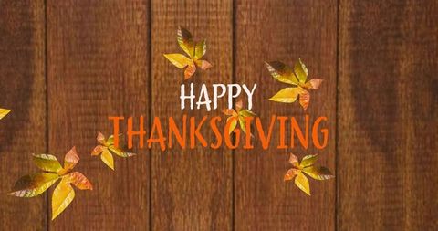Rustic hand-lettered happy thanksgiving typography on wood plank with falling autumn leaves