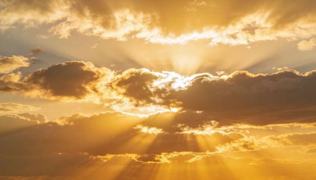 Golden crepuscular rays breaking through dramatic cloud band at sunrise or sunset