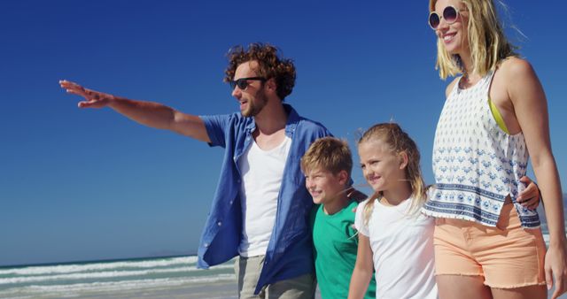 Relaxing Caucasian Family Enjoying Sunny Beach Day with Father Pointing in Distance - Download Free Stock Images Pikwizard.com