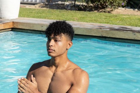 African american man standing chest-deep in pool showing hoop earring and athletic physique