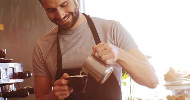 Smiling Barista Pouring Milk into Coffee Cup in Sunlit Cafe - Download Free Stock Images Pikwizard.com