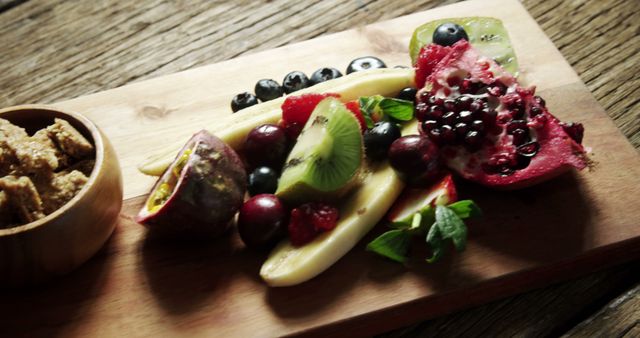 Colorful arrangement of sliced exotic fruits including pomegranate, kiwi, berries, and a side of grainy snack on a wooden board. Ideal for use in a healthy eating blog, vegetarian recipes, or food presentation articles emphasizing fresh, nutritious foods. Perfect for ads highlighting natural food options or promoting vegan lifestyle.
