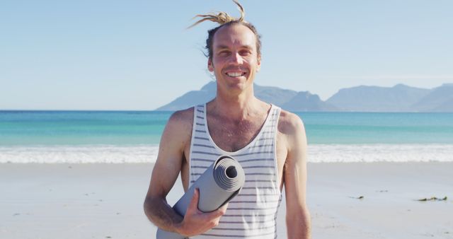 Man Holding Yoga Mat on Beach Smiling at Camera - Download Free Stock Images Pikwizard.com