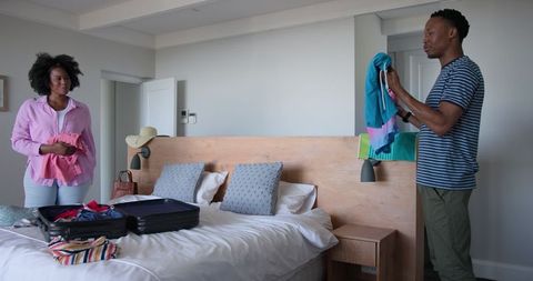 Couple Packing for Vacation in Modern Bedroom
